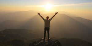 Person celebrating on mountain peak at sunrise