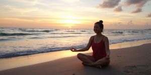 Person meditating on beach at sunrise